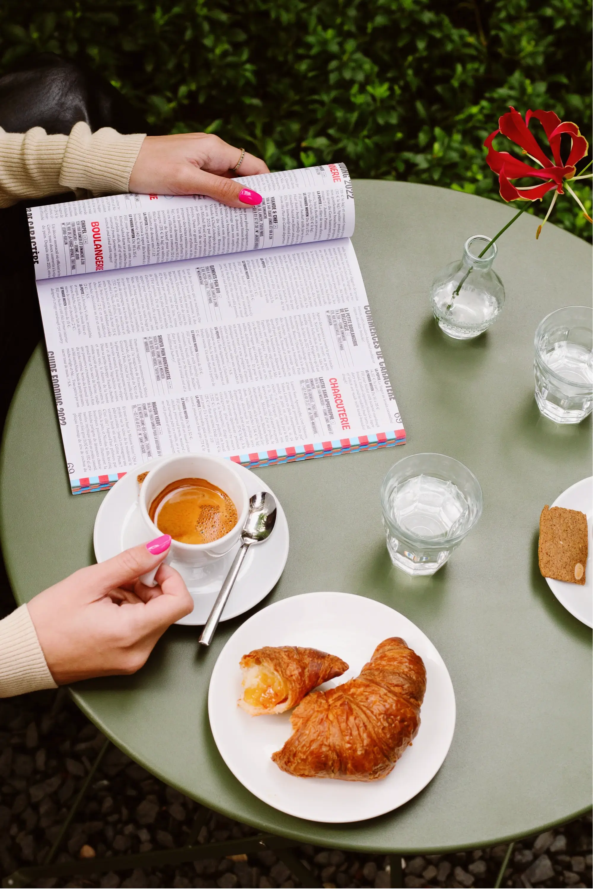 Person sitting at a round restaurant table with a coffee and croissant looking into restaurant recommendations guide